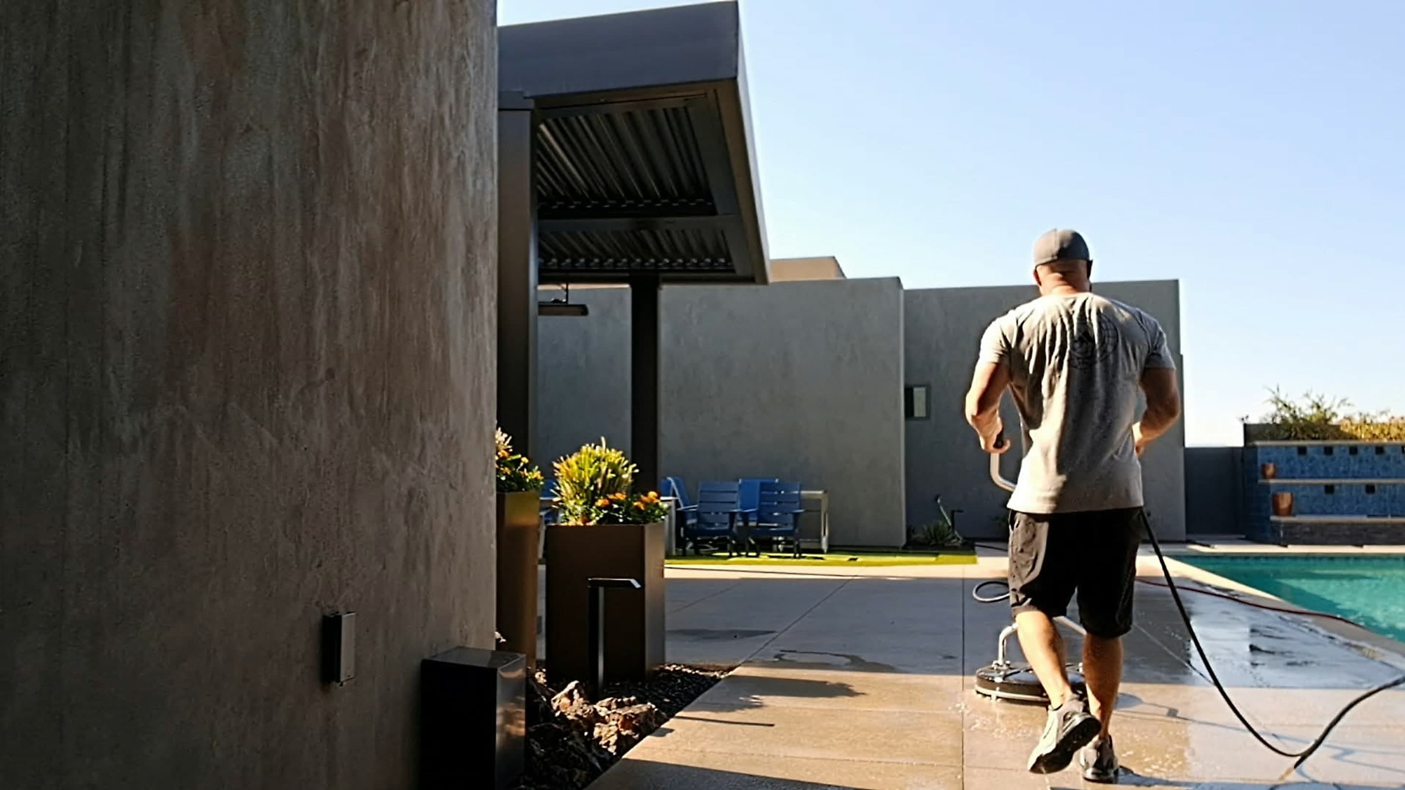 Technician surface cleaning a pool deck at a modern desert home